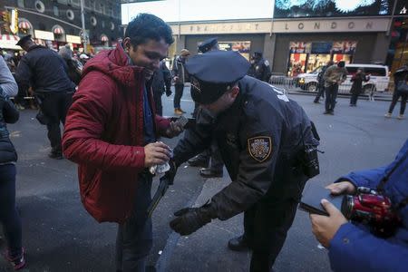 A man is scanned with a wand by a member of the New York Police Department as he tries to enter a penned area of Times Square during New Year's Eve celebrations in the Manhattan borough of New York December 31, 2015. REUTERS/Carlo Allegri