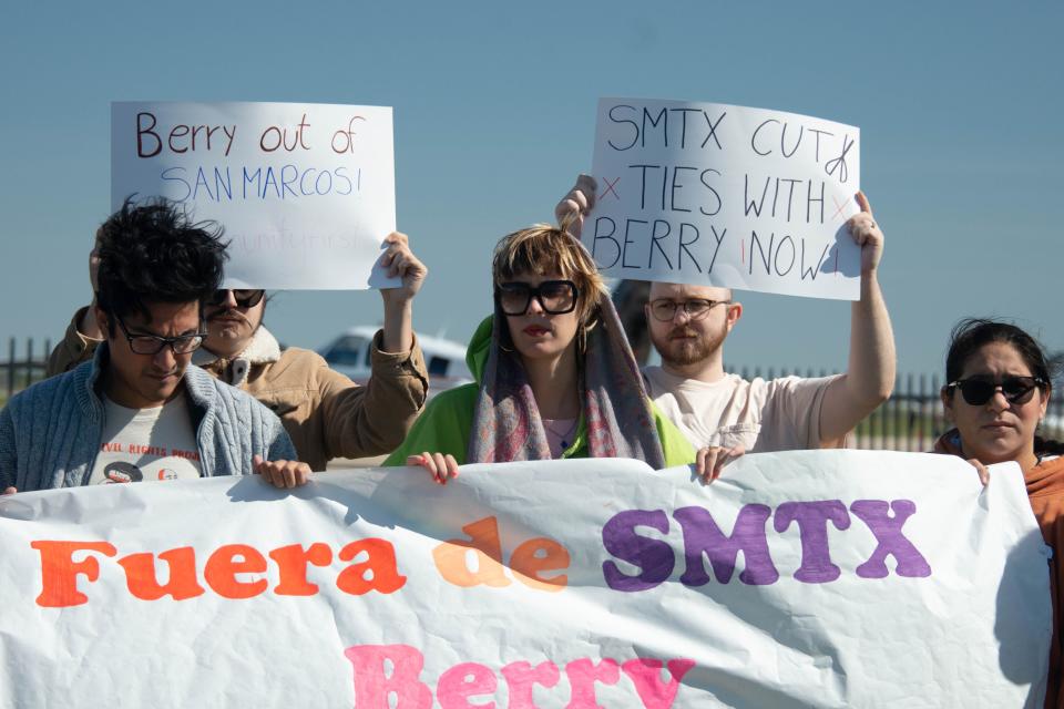 Roberto Lopez, Elle Cross and Ilse Hernandez hold a banner in front of Berry Aviation at the San Marcos Regional Airport during a protest Oct. 15. California's attorney general has named Berry Aviation as part of an investigation into migrants being flown to Sacramento via a Florida-run migrant program.