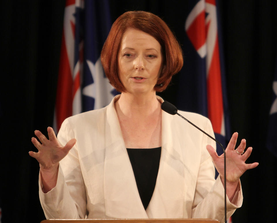 Julia Gillard standing in front of Australian flags addressing the media