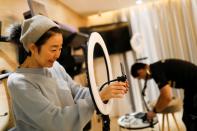 Liu Xiaojin, sets up a phone as she gets ready to livestream a gym class, as the country is hit by an outbreak of the new coronavirus, in Beijing