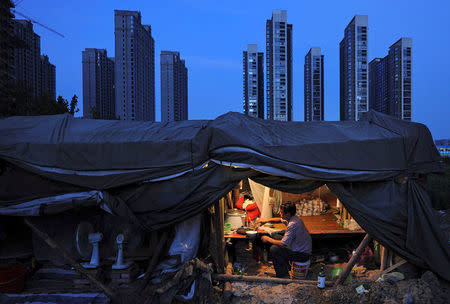 FILE PHOTO: A labourer has his dinner under his shed at a construction site of a residential complex in Hefei, Anhui province, August 1, 2012. REUTERS/Stringer/File Photo