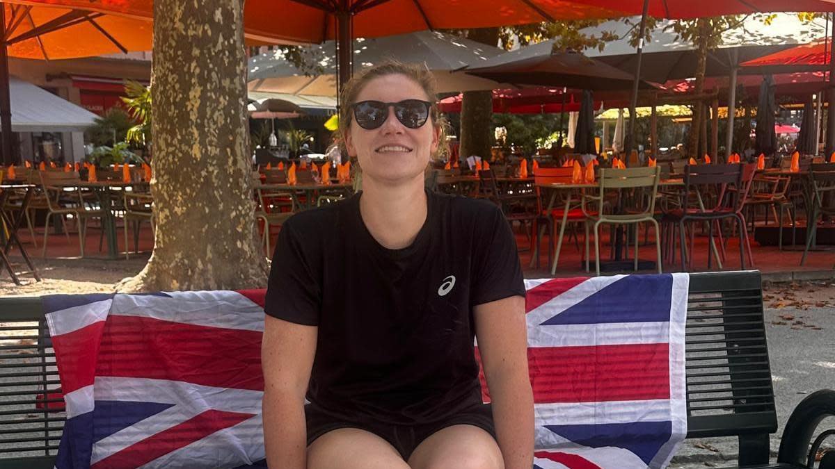 Sam Farrow sitting on a bench with a Union flag behind her 