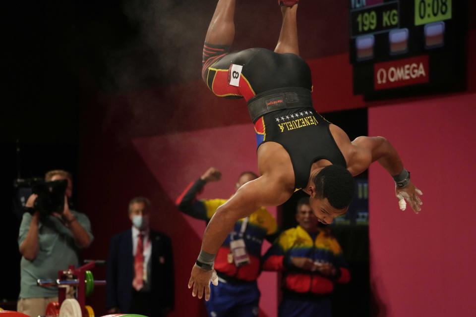 Julio Ruben Mayora Pernia of Venezuela twirls after winning the silver medal in the men's 73kg weightlifting event, at the 2020 Summer Olympics, Wednesday, July 28, 2021, in Tokyo, Japan. (AP Photo/Luca Bruno)