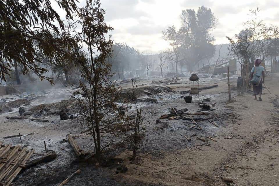 A resident walks past smoldering houses in the Kinma village, Pauk township, Magwe division, central Myanmar, Wednesday, June 16, 2021. Residents said people are missing after military troops burned the village the night before. (AP Photo)