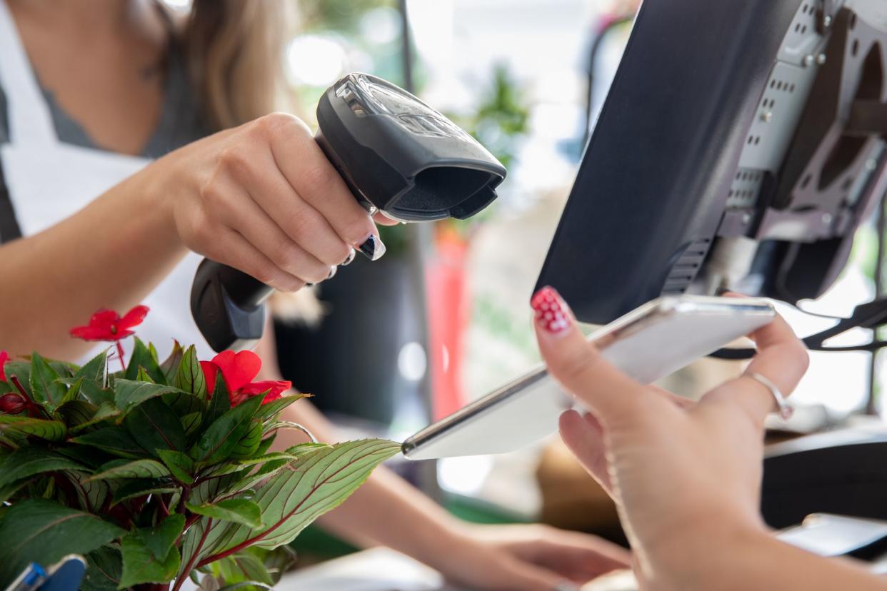 Employee scans smart phone to take payment at garden center or plant nursery