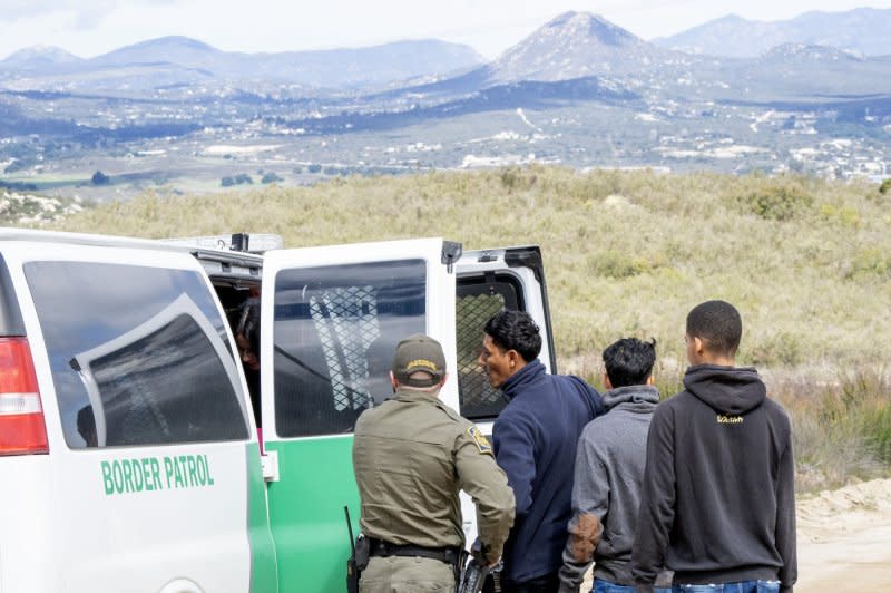 Migrants are placed into vans by the U.S. Border Patrol after crossing the border wall from Mexico near Campo, Calif., about 50 miles from San Diego, on March 13. File Photo by Pat Benic/UPI