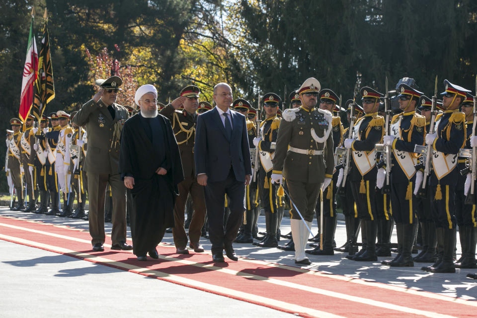 In this photo released by official website of the Office of the Iranian Presidency, Iraqi President Barham Salih, center, reviews an honor guard as he is welcomed by his Iranian counterpart Hassan Rouhani, in white turban, during an official welcome ceremony at the Saadabad Palace in Tehran, Iran, Saturday, Nov. 17, 2018. Salih is visiting Iran less than two weeks after the United States restored oil sanctions that had been lifted under the 2015 nuclear deal. (Iranian Presidency Office via AP)
