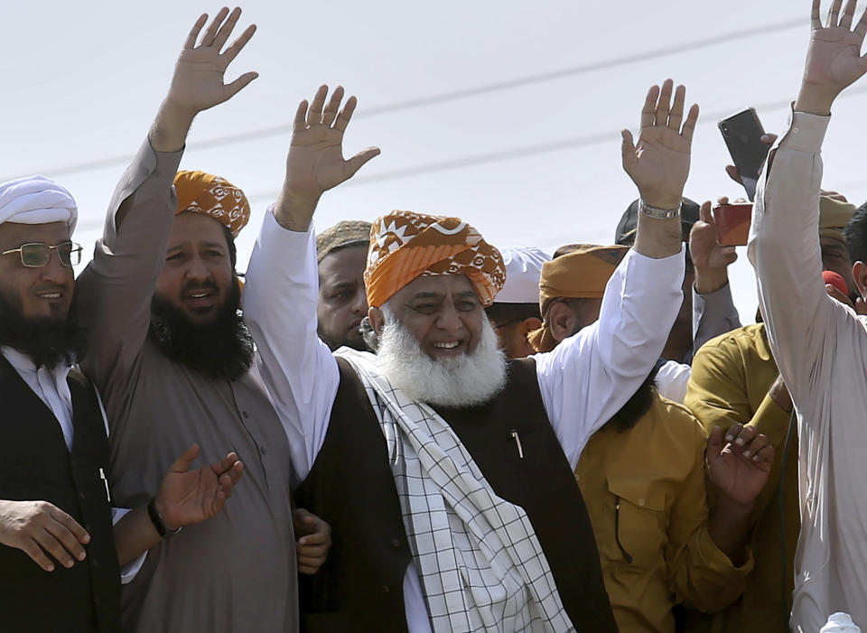 Maulana Fazlur Rehman, center, head of the Jamiat Ulema-e-Islam party, waves to supporters on his arrival to lead an anti-government march, in Karachi, Pakistan, Sunday, Oct. 27, 2019. Thousands of supporters of the ultra-religious party are gathering in Karachi to start a large anti-government march on Pakistan's capital farther north. (AP Photo/Fareed Khan)