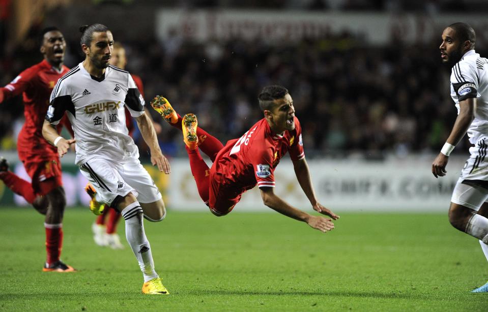 Swansea City's Chico Flores (L) challenges Liverpool's Philippe Coutinho (C) during their English Premier League soccer match at the Liberty Stadium in Swansea, Wales September 16, 2013.