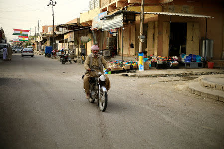 A man rides a motorbike in Kurdish neighbourhood in Tuz Khurmato, Iraq September 24, 2017. REUTERS/Thaier Al-Sudani