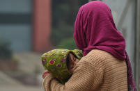 <p>An Indian woman carries her son as she waits for a bus amid fog in New Delhi on December 13, 2017. (Photo by Prakash Singh/AFP/Getty Images) </p>