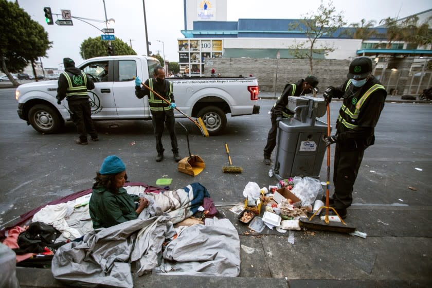 An Urban Alchemy cleaning crew gather before dawn to meet before cleaning the street of skid row with shovels and brooms.