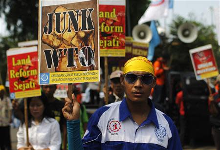 Protesters holds a signs against the ninth World Trade Organization (WTO) Conference in front of United States embassy in Jakarta, December 6, 2013. Ministers from nearly 160 member countries of the World Trade Organisation entered a final day of negotiations in Bali on Friday with officials sounding optimistic over chances of salvaging a deal that would save the trade body from sliding into irrelevance. REUTERS/Beawiharta