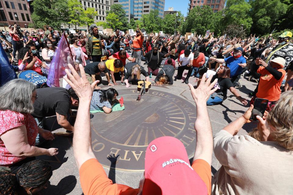 Members of the Shiloh Christian Center pray and sing on the "With God All Things Are Possible" seal on the west lawn of the Ohio Statehouse.