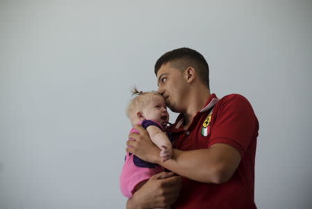 Rogerio dos Santos, 20, holds his daughter, 4-month-old Heloa Vitoria, who was born with microcephaly, at Pedro I Hospital in Campina Grande, Brazil February 18, 2016. REUTERS/Ricardo Moraes