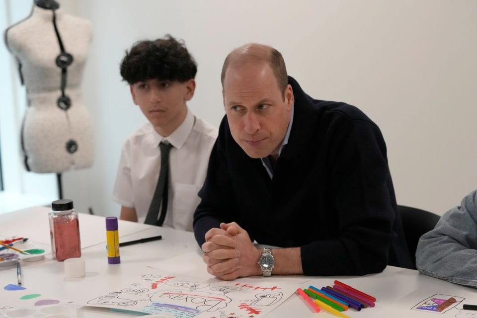 Prince William listens as he interacts with young people during his visit (AP)