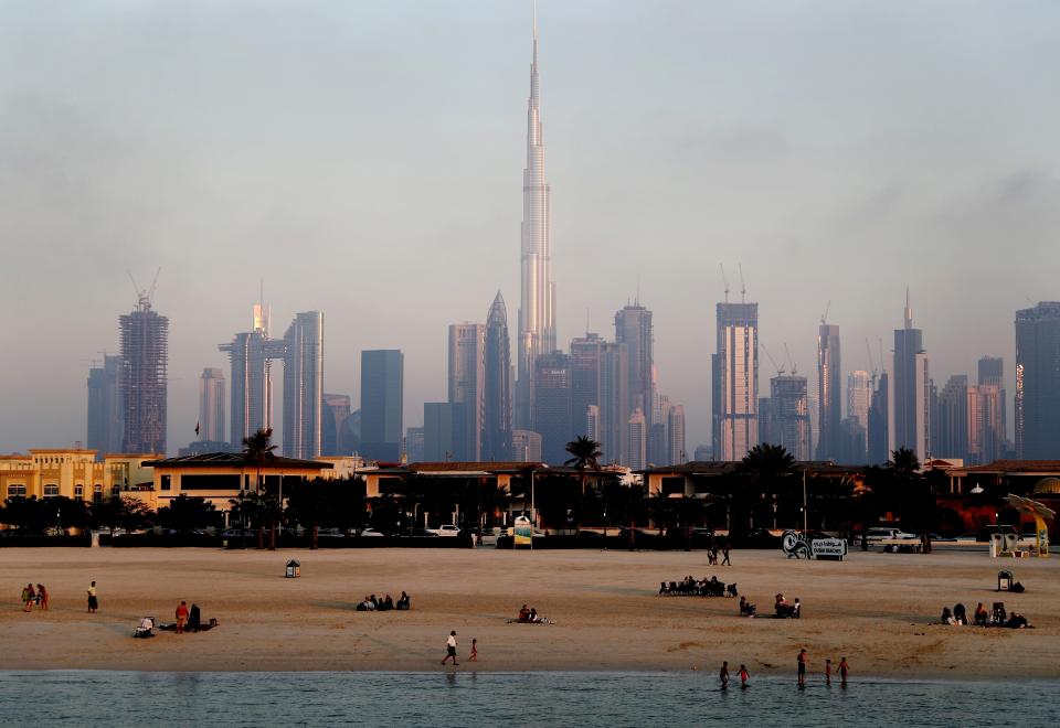FILE - People enjoy the beach in front of the city skyline with the world tallest tower, Burj Khalifa, in Dubai, United Arab Emirates, Friday, Feb. 12, 2021. The globalized city-state of Dubai appears to be in the midst of a boom season. It's a surge in growth spurred on by one of the world’s highest vaccination rates and government moves to de-escalate tensions with regional rivals and lure foreign businesses. (AP Photo/Kamran Jebreili, File)