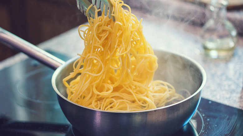 Tongs pulling spaghetti out of pan 