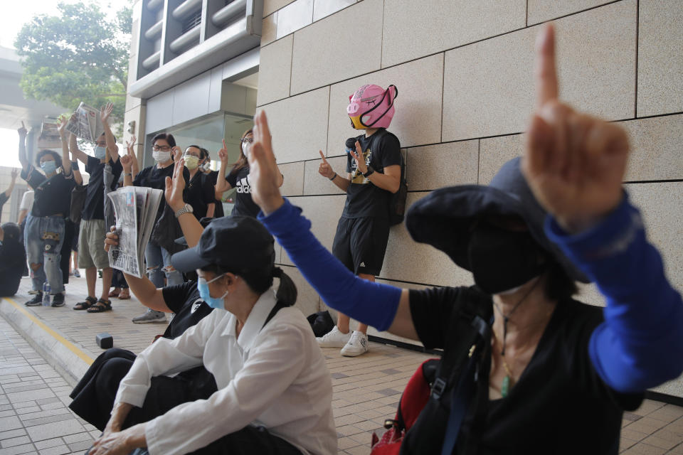 Protesters gesture with five fingers, signifying the "Five demands - not one less" outside a court during a protest in Hong Kong, Thursday, Aug. 27, 2020. Hong Kong police arrested 16 people, including two opposition lawmakers, on Wednesday on charges related to anti-government protests last year. (AP Photo/Kin Cheung)