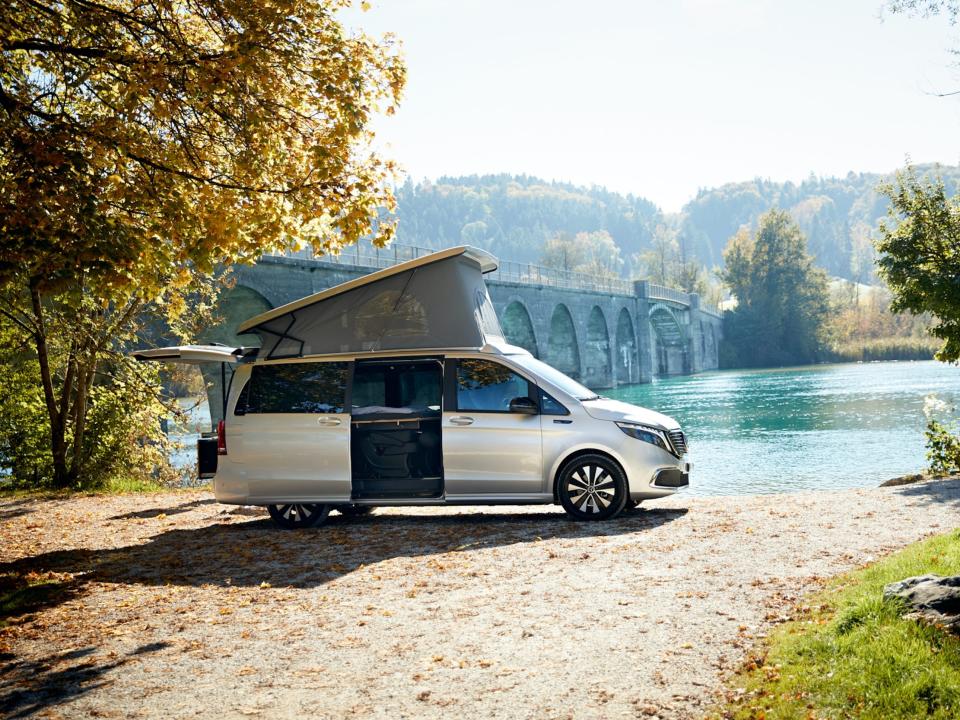 Mercedes-Benz EQV by the water near trees.