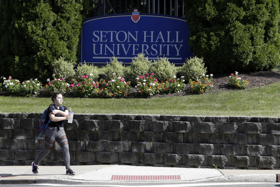 A person walks near a sign outside of Seton Hall University, Thursday, Aug. 23, 2018, in South Orange, N.J. The university has begun an investigation into potential sexual abuse at two seminaries it hosts following misconduct allegations against ex-Cardinal Theodore McCarrick and other priests. In a letter posted to the university's website Wednesday, President Mary Meehan referred to the recent accusations against McCarrick, who served as Archbishop of Newark from the mid-1980s until the early 2000s. The Vatican removed McCarrick from public ministry in June after it determined allegations he molested a teenager more than 40 years earlier were credible. (AP Photo/Julio Cortez)