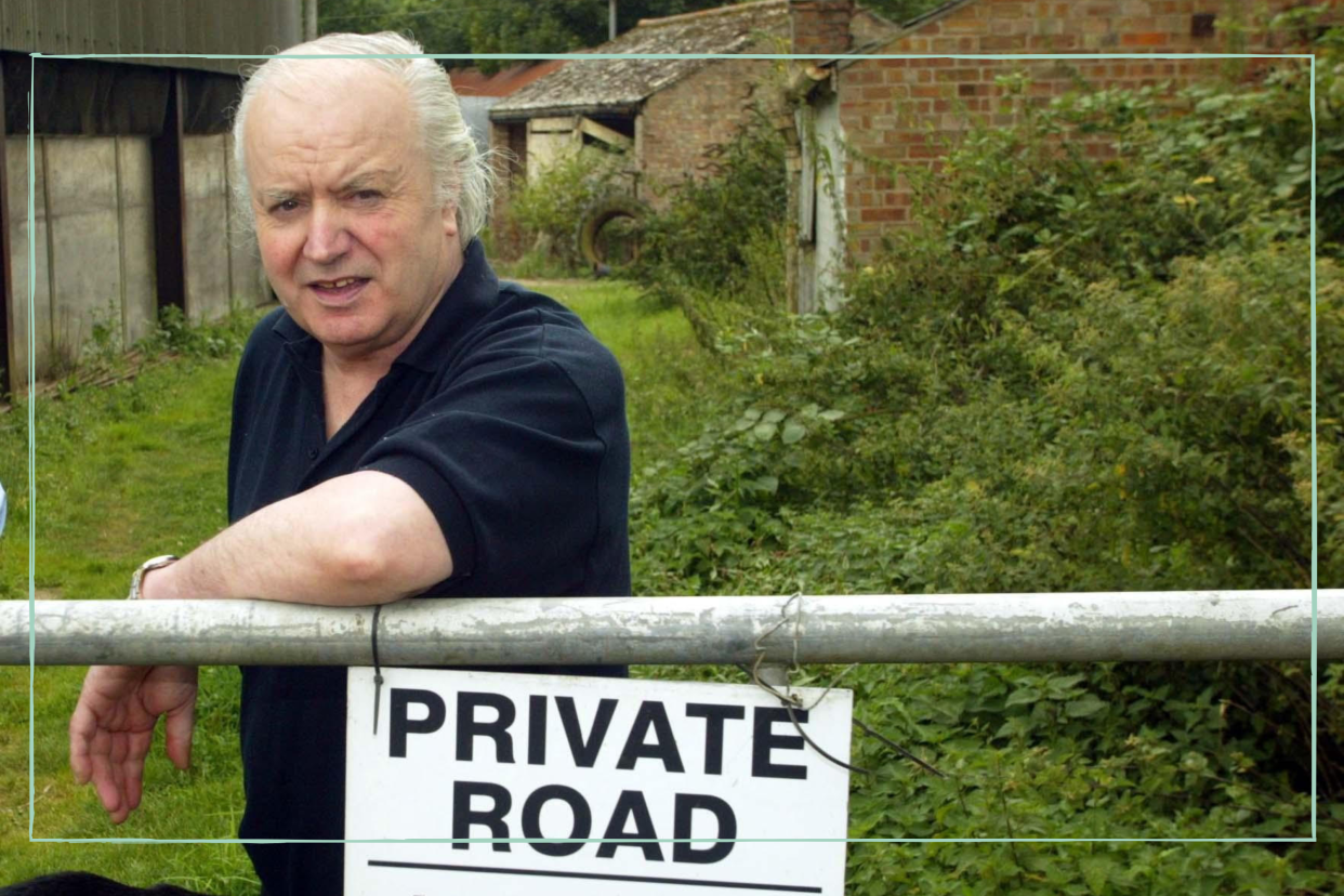  Tony Martin leaning on a fence with a 'Privat Road' sign attached to it 