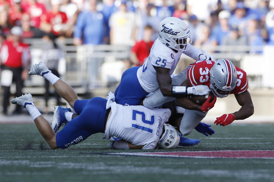 Ohio State running back Master Teague, right, is tackled by Tulsa defensive backs Bryson Powers, bottom, and Jaise Oliver during the first half of an NCAA college football game Saturday, Sept. 18, 2021, in Columbus, Ohio. (AP Photo/Jay LaPrete)