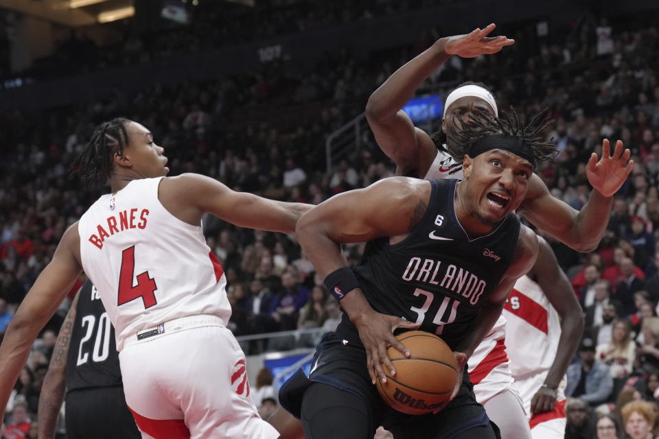 Orlando Magic's Wendell Carter Jr. claims an offensive rebound in front of Toronto Raptors' Scottie Barnes (4) and Precious Achiuwa during the second half of an NBA basketball game in Toronto on Tuesday, Feb. 14, 2023. (Chris Young/The Canadian Press via AP)