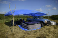 In this Friday, Jan. 10 photo, residents from the Indios neighborhood of Guayanilla, Puerto Rico, shade themselves under a tarp on a private hay farm where locals affected by earthquakes have set up shelter amid aftershocks in Guayanilla, Puerto Rico. A 6.4 magnitude quake that toppled or damaged hundreds of homes in southwestern Puerto Rico is raising concerns about where displaced families will live, while the island still struggles to rebuild from Hurricane Maria two years ago. (AP Photo/Carlos Giusti)