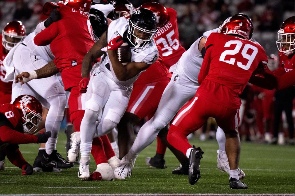 Cincinnati Bearcats running back Corey Kiner (21) runs for a touchdown as Houston Cougars linebacker Treylin Payne (29) and Houston Cougars defensive back Juwon Gaston (21) attempt to stop him in the fourth quarter of the NCAA football game between the Cincinnati Bearcats and the Houston Cougars TDECU Stadium in Houston, Texas, on Saturday, Nov. 11, 2023.