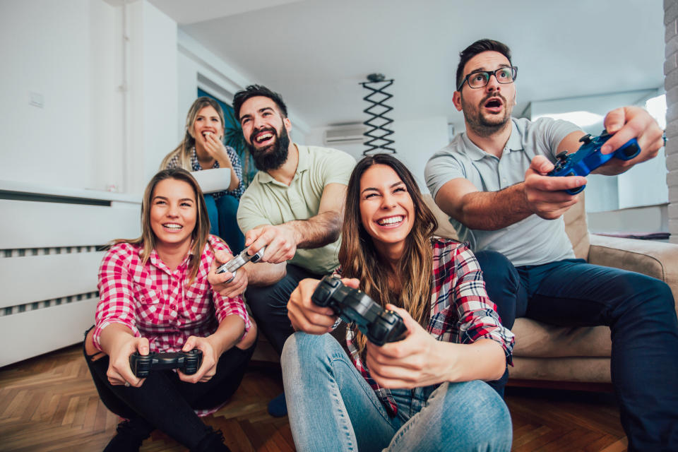 A group of friends play a video game in a living room.