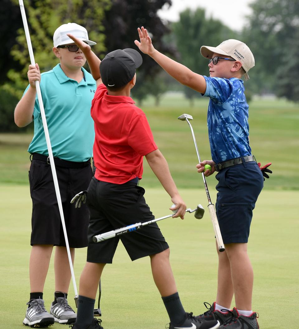 Great sportsmanship as Issac Scott (center) of Dundee high fives Grayson Cunningham (right) of Ida after making a par putt along with Liam Doll of Tecumseh during the 44th annual La-Z-Boy Junior Open on Wednesday at Green Meadows. All three players parred the 14th hole.