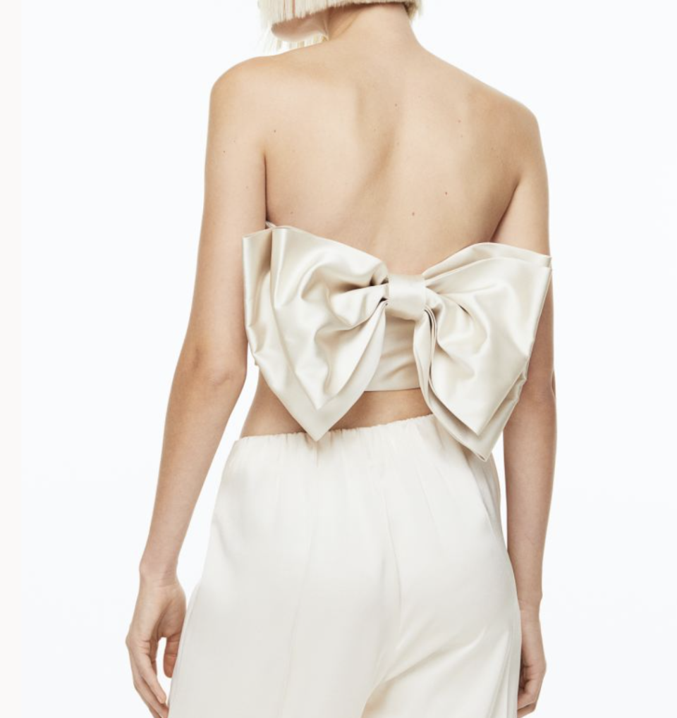 A photo of a model wearing a cropped bow-back top.