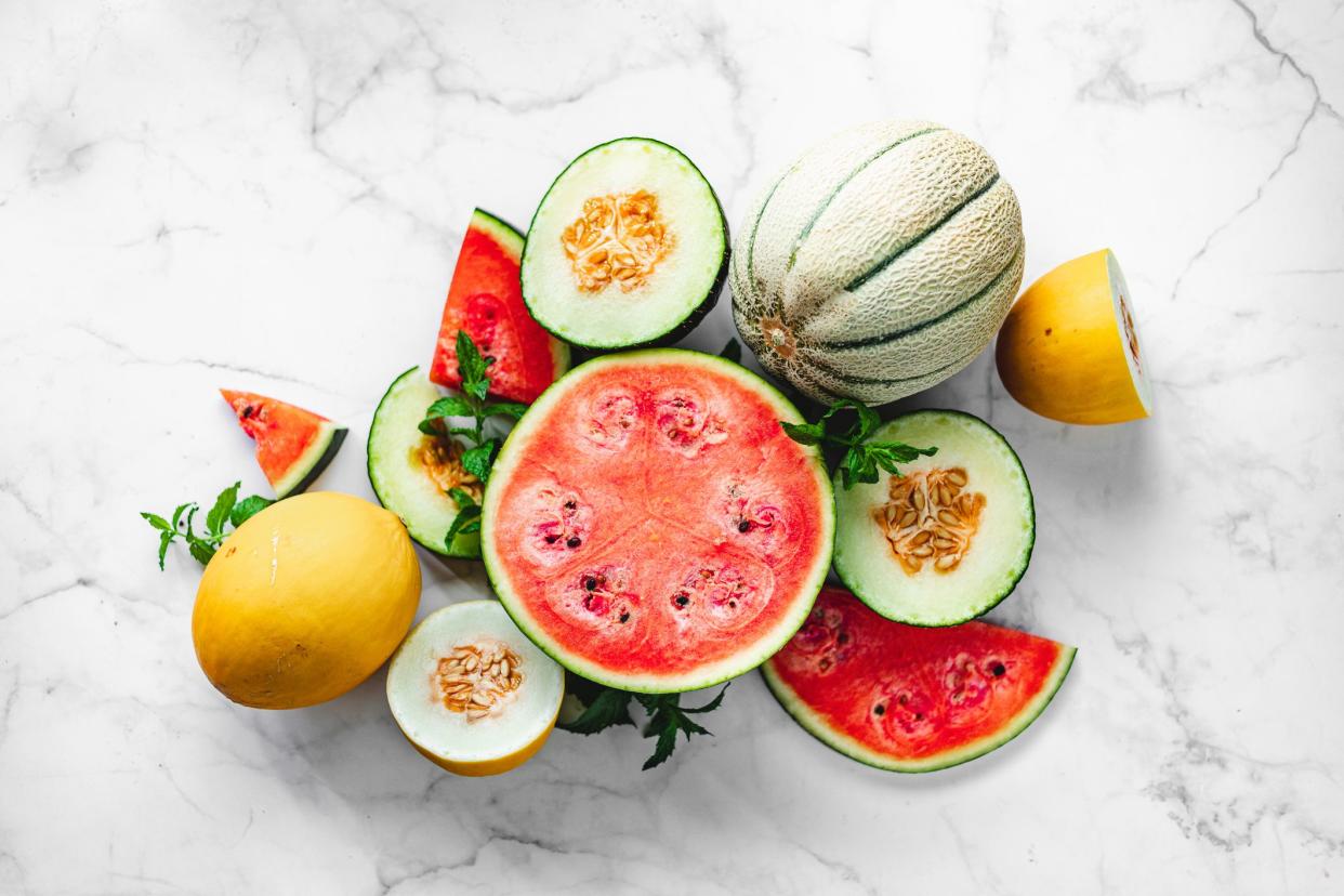 Directly above shot of exotic tropical fruits on white background.  Various types of melons slices pver marble surface.