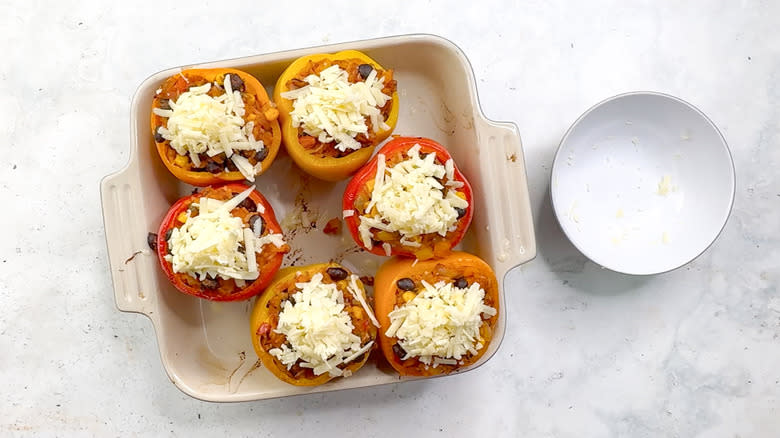 bell peppers stuffed with cheese, rice, beans and corn in baking dish