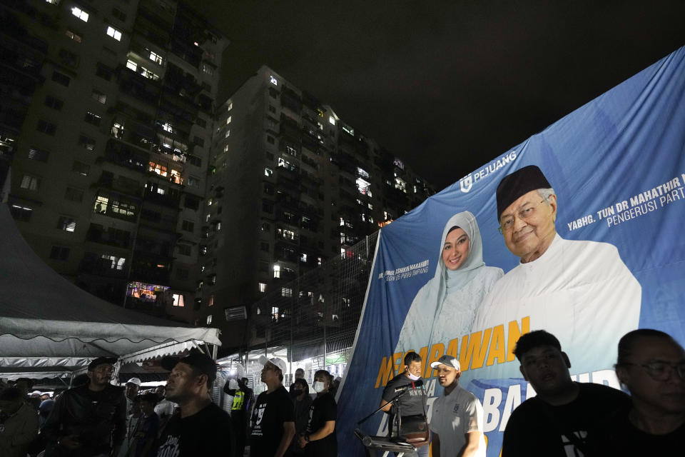 A giant poster shows two-time former Malaysian Prime Minister and Gerakan Tanah Air, or Homeland Movement Chairman Mahathir Mohamad, right, at a rally for his party in Kuala Lumpur, Malaysia, Tuesday, Nov. 15, 2022. At 97, Mahathir is back again in the election race as the head of a new ethnic Malay alliance that he calls a "movement of the people." He hopes his bloc could gain enough seats in Nov. 19 polls to be a powerbroker. (AP Photo/Vincent Thian)