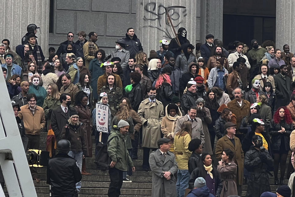 Throngs of actors portraying protesters, some in make-up, gather outside a courthouse for the filming of a scene in the "Joker" movie sequel in New York, Saturday, March 25, 2023. Production crews had to wrestle with the possibility that filming could be disrupted by real-life protests over the Trump case, none of which have materialized so far. (AP Photo/Bobby Caina Calvan)