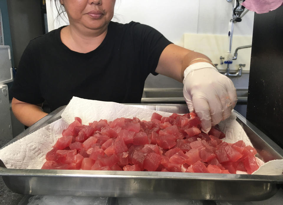 This Tuesday, April 16, 2019 photo shows Michele Miyanaga preparing cubes of raw ahi, or tuna, at Aloha Poke Shop, a store in Honolulu that received a letter from Chicago-based Aloha Poke Co. saying the Illinois company had trademarked "Aloha Poke" and the Hawaii company would need to change its name. Hawaii lawmakers are considering adopting a resolution calling for the creation of legal protections for Native Hawaiian cultural intellectual property. (AP Photo/Audrey McAvoy)