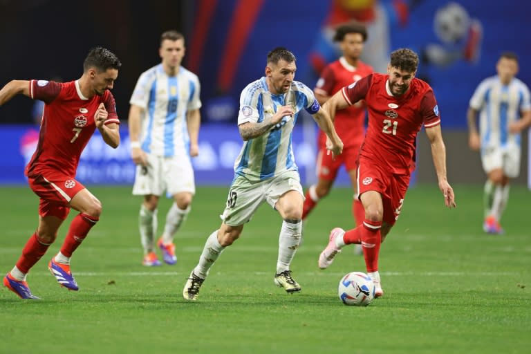 Lionel Messi (C) se lleva el balón ante dos jugadores de Canadá en el partido inaugural de la Copa América-2024 el 20 de junio de 2024 en Atlanta, Georgia (CHARLY TRIBALLEAU)