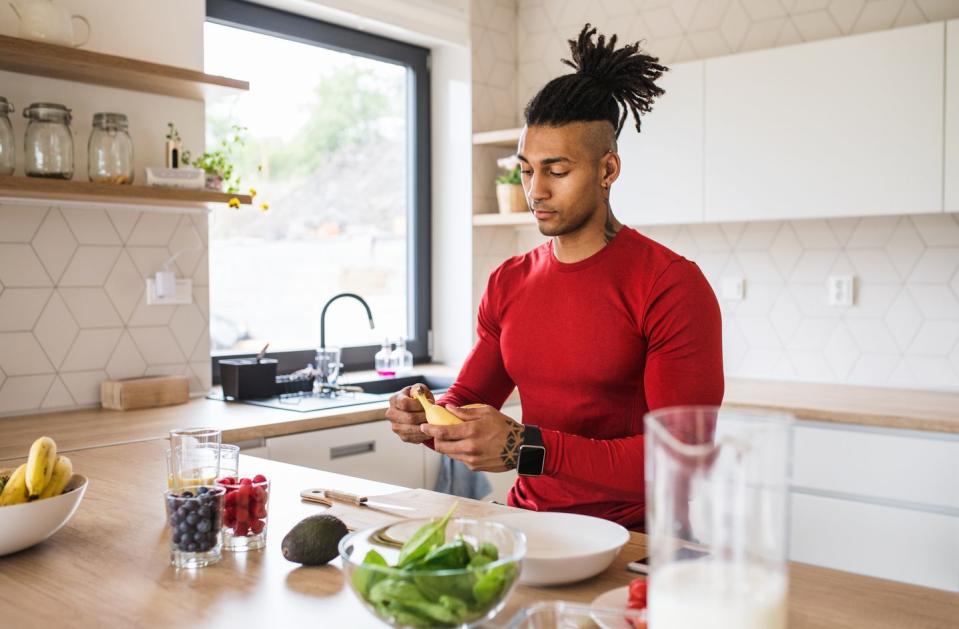 a portrait of fit mixed race man with dreadlocks in kitchen at home preparing healthy food