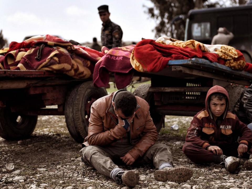 Relatives mourn next to bodies of Iraqi residents of west Mosul killed in an air strike targeting Isis on 17 March 2017 (AFP/Getty)