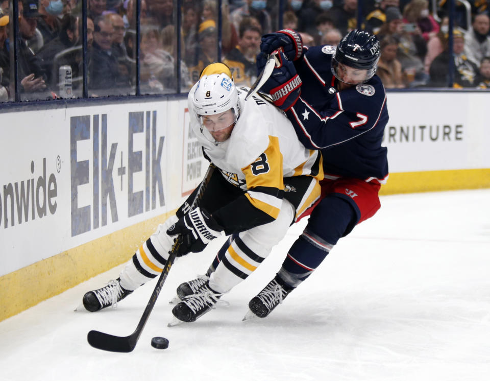 Pittsburgh Penguins defenseman Brian Dumoulin, left, controls the puck in front of Columbus Blue Jackets forward Sean Kuraly during the second period of an NHL hockey game in Columbus, Ohio, Friday, Jan. 21, 2022. (AP Photo/Paul Vernon)