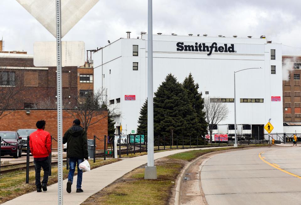 Employees walk into work March 24 at the Smithfield Foods plant in Sioux Falls, S.D.