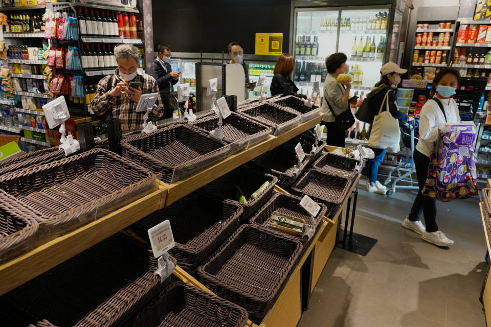 Produce shelves sit empty as residents make purchases on fears of shortages at a supermarket in Hong Kong, Monday, Feb. 28, 2022. Hong Kong on Monday reported a record-high 34,466 infections, with health authorities saying that a lockdown has not been ruled out as fatalities continued to climb. (AP Photo/Vincent Yu)