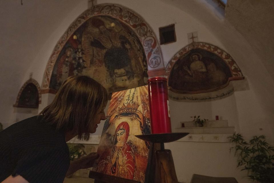 A woman kisses a portrait of the Virgin Mary after praying in the ancient Qannoubine Monastery, hidden deep in the Kadisha Valley, a holy site for Lebanese Maronite Christians, in the northeast mountain town of Bcharre, Lebanon, Saturday, July 22, 2023. For Lebanon's Christians, the cedars are sacred, these tough evergreen trees that survive the mountain's harsh snowy winters. They point out with pride that Lebanon's cedars are mentioned 103 times in the Bible. (AP Photo/Hassan Ammar)