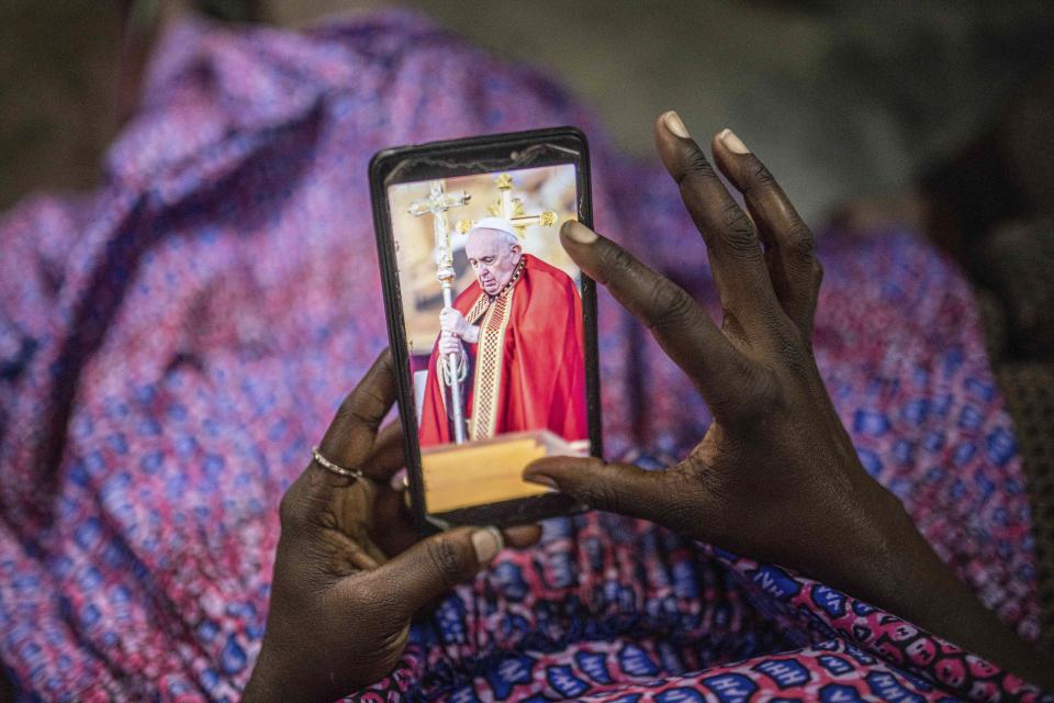 Marie Louise Wambale looks at a photograph of Pope Francis on her telephone in Goma, Democratic Republic of the Congo, Saturday Jan. 21, 2023. Like most Catholics here in eastern Congo, she hopes that Pope Francis can bring a message of hope at a time when the M23 rebels are posing their greatest threat since 2012. Pope Francis will be in Congo and South Sudan for a six-day trip starting Jan, 31 2023. (AP Photo/Moses Sawasawa)