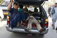 Afghan volunteers carry an injured man in a local taxi after a car bomb attack in western Kabul