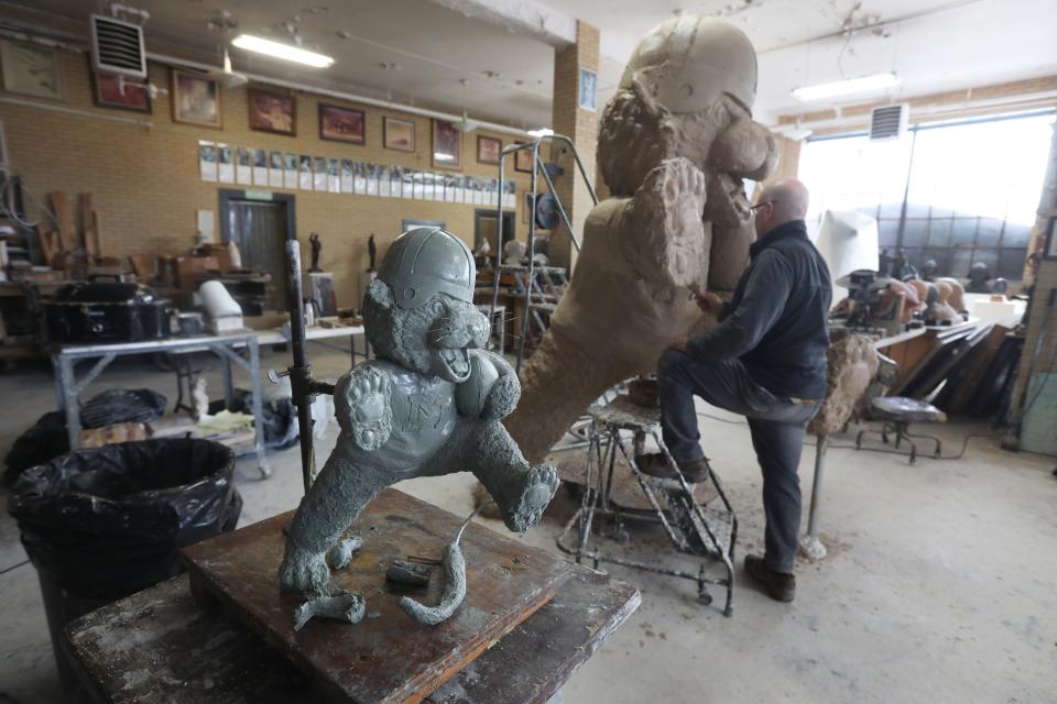 A smaller model stands in the foreground as sculptor Alan Cottrill works on a statue of Massillon Tigers mascot Obie in his Zanesville studio.