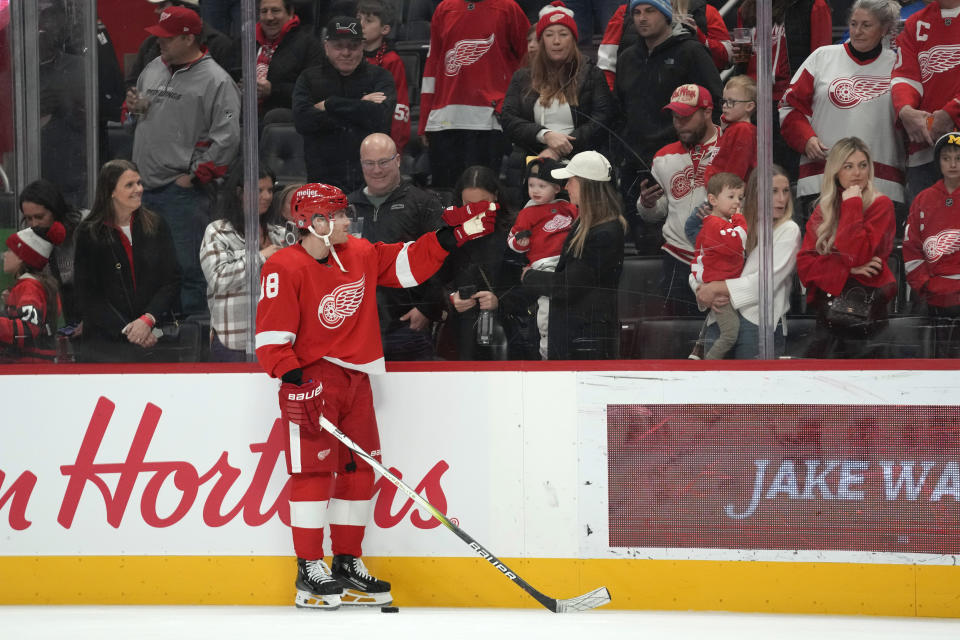 Detroit Red Wings' Patrick Kane (88) taps the glass after flipping a puck to a child during warms up before an NHL hockey game against the San Jose Sharks, Thursday, Dec. 7, 2023, in Detroit. (AP Photo/Paul Sancya)