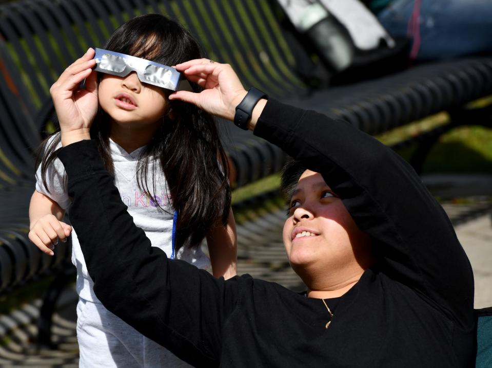 Megan Carandang, 4, shares her mother Phoebe Yap's glasses as they watch the partial solar eclipse on the Worcester Common.